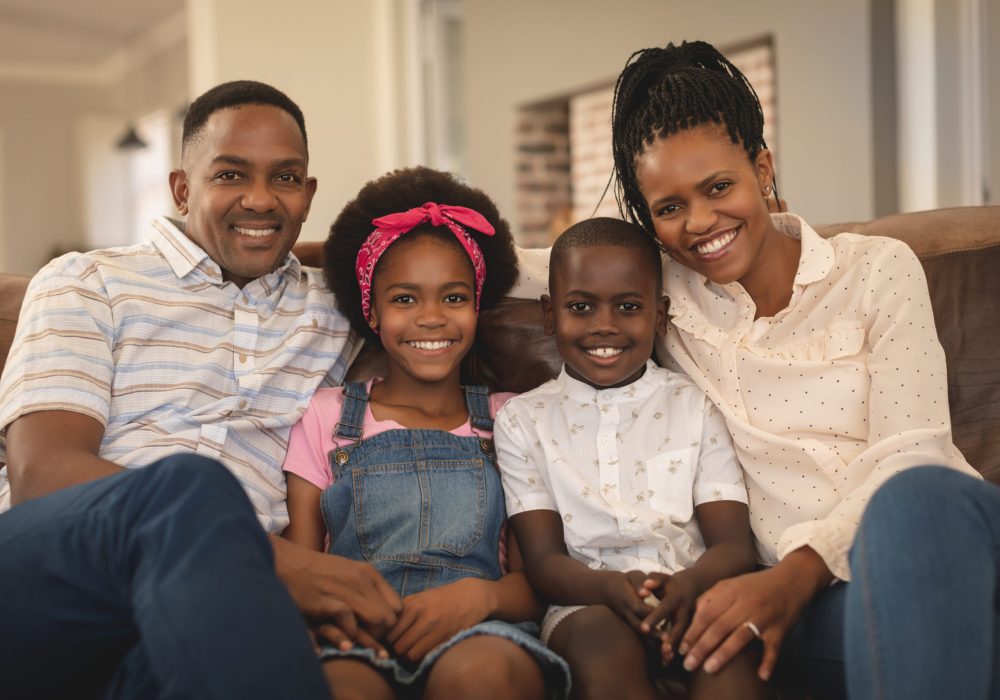 Portrait of happy African American family sitting on the sofa and looking at camera in a comfortable home